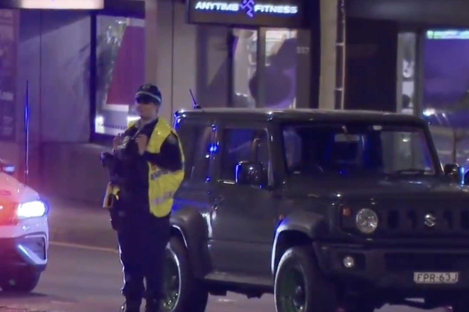 Red-Light NSW Police at the scene of a crash on the Pacific Highway in St Leonards on Monday evening. Alt text: NSW Police officers at a crash scene on the Pacific Highway in St Leonards at night