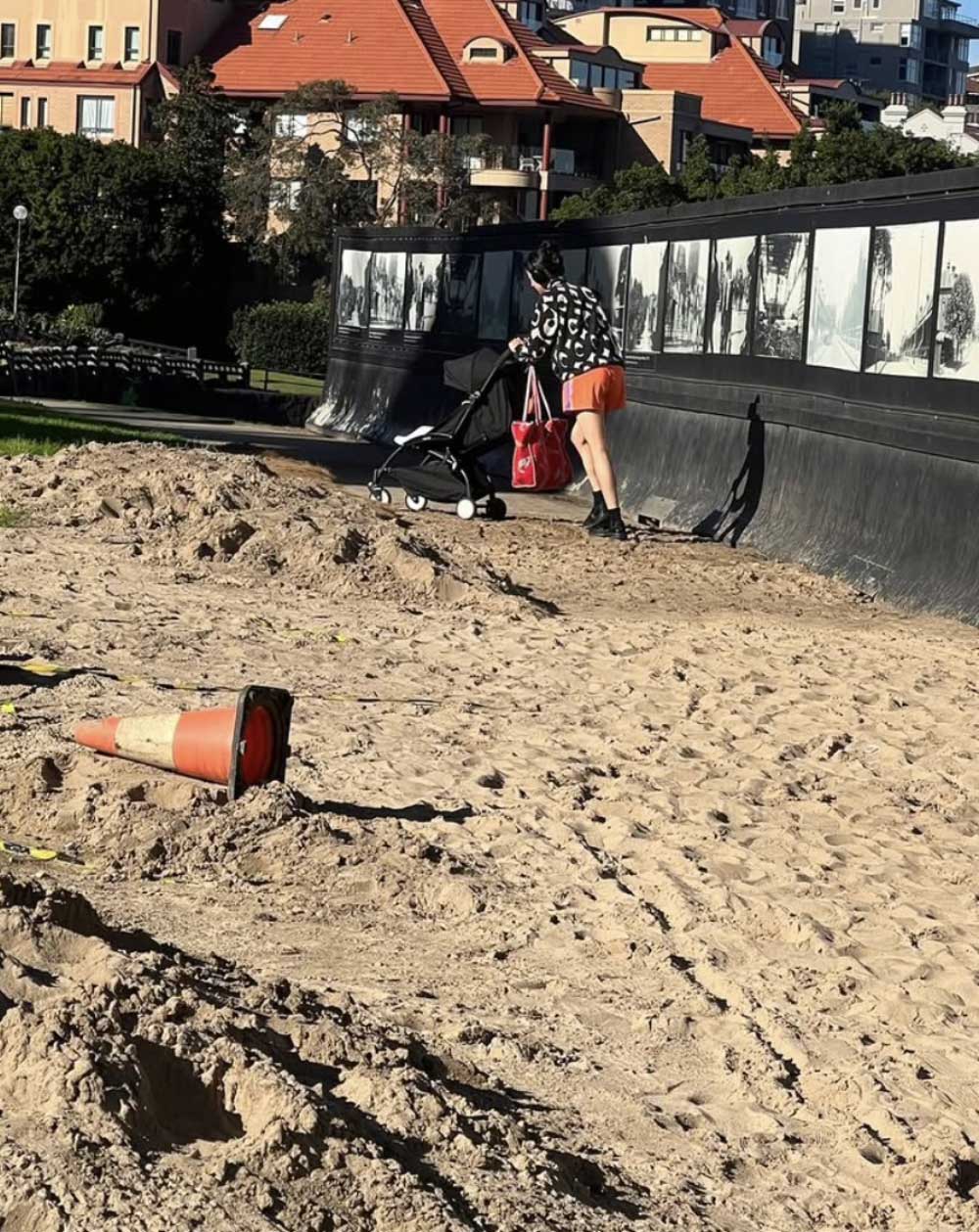 A young Mum pushes a pram through bare ground on Bradfield Park South.