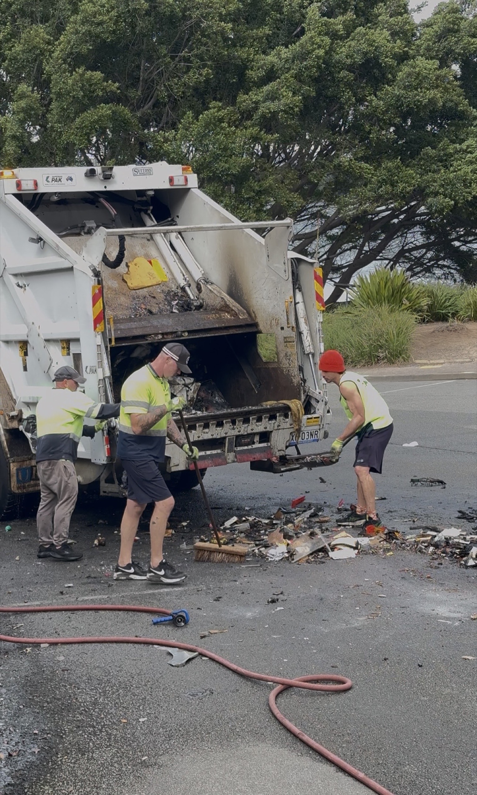 Council workers clean up burnt rubbish tipped from a fire-damaged garbage truck at Kirribilli.