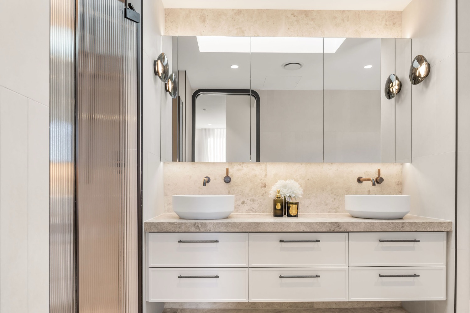 The ensuite in the Park Residences penthouse at Cremorne, with twin stone basins, mirrored cabinetry and sculptural wall lights.