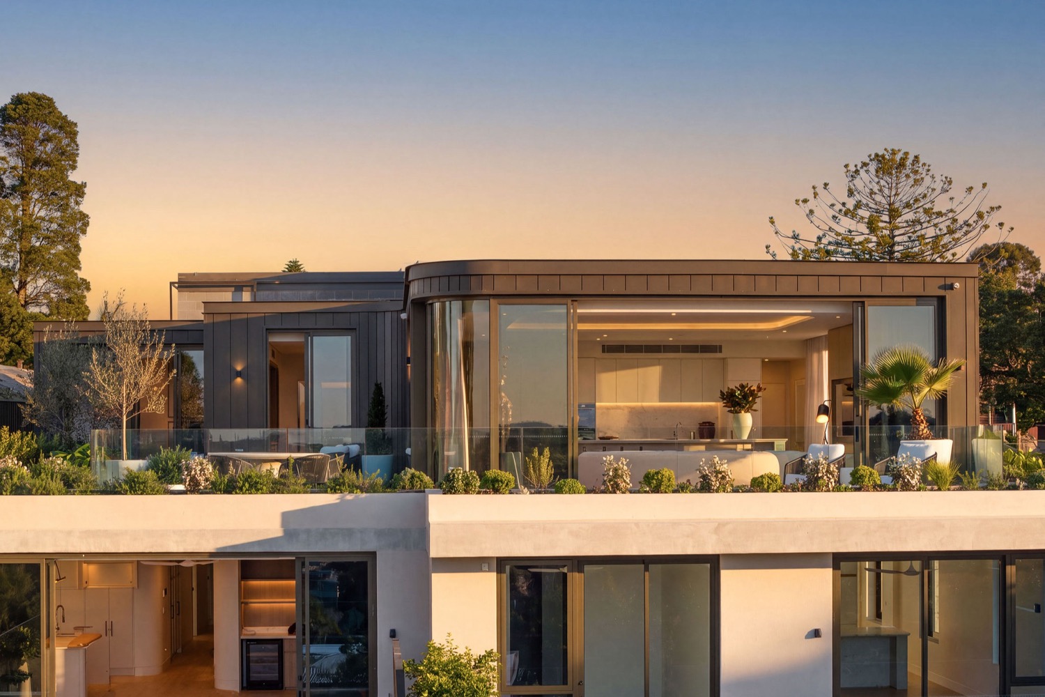 The Park Residences penthouse at Cremorne seen from the front at sunset, with the living space and kitchen opening onto the planted terrace.