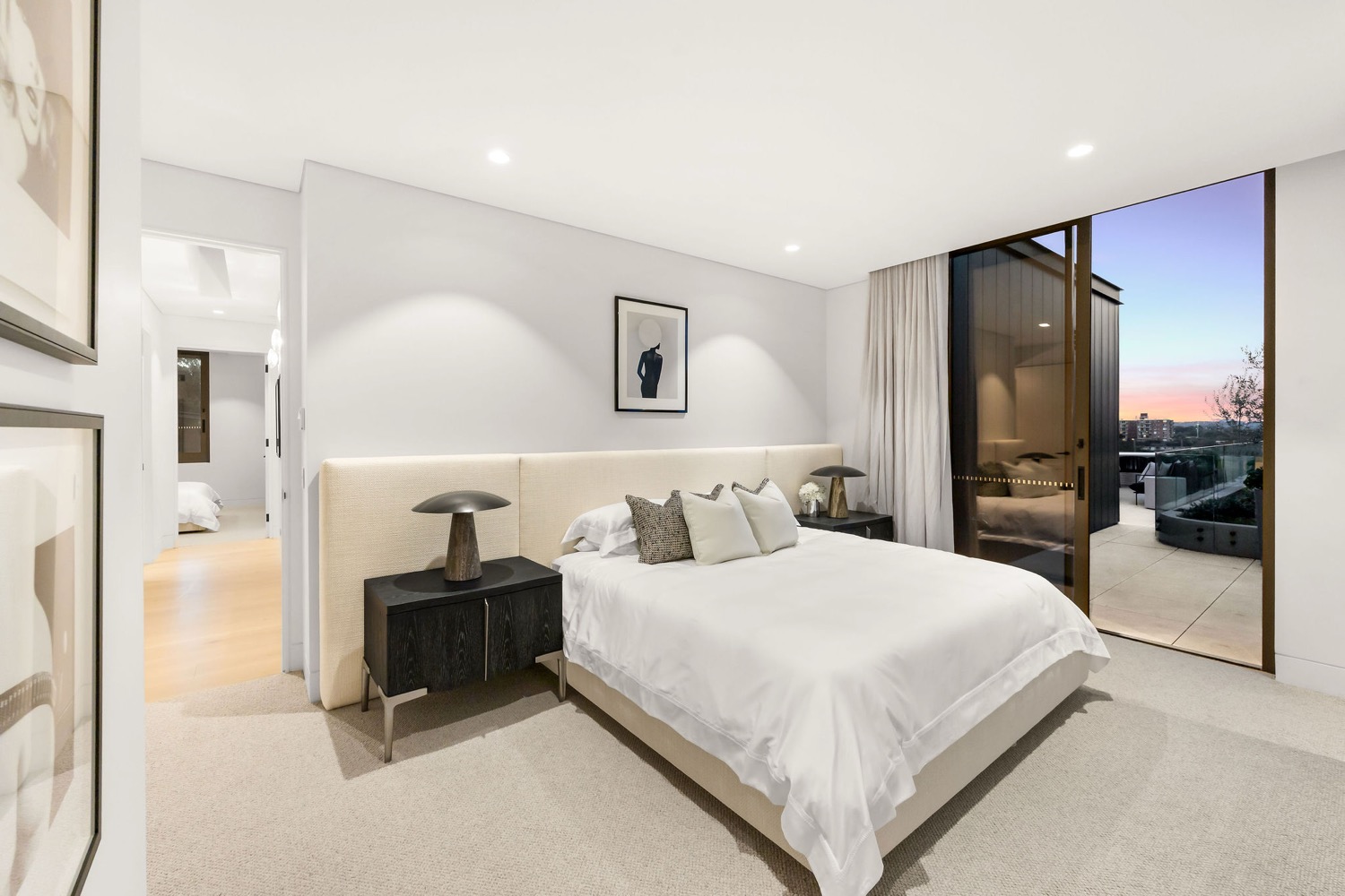 The main bedroom of the Park Residences penthouse in Cremorne, with a sliding door opening onto the terrace at dusk.