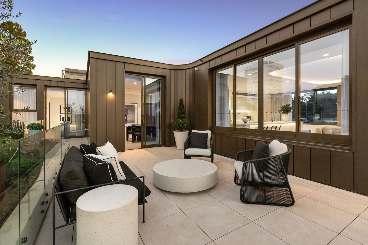 The wraparound terrace at the Park Residences penthouse in Cremorne at dusk, with lounge seating outside the bedroom and kitchen windows.
