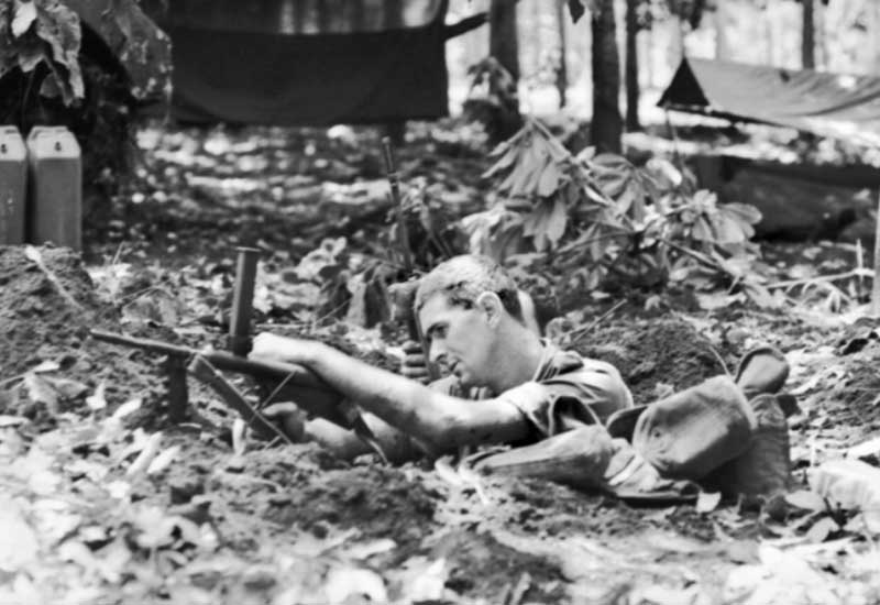 An Australian soldier lies in a shallow weapon pit with his rifle at a jungle position in Vietnam.