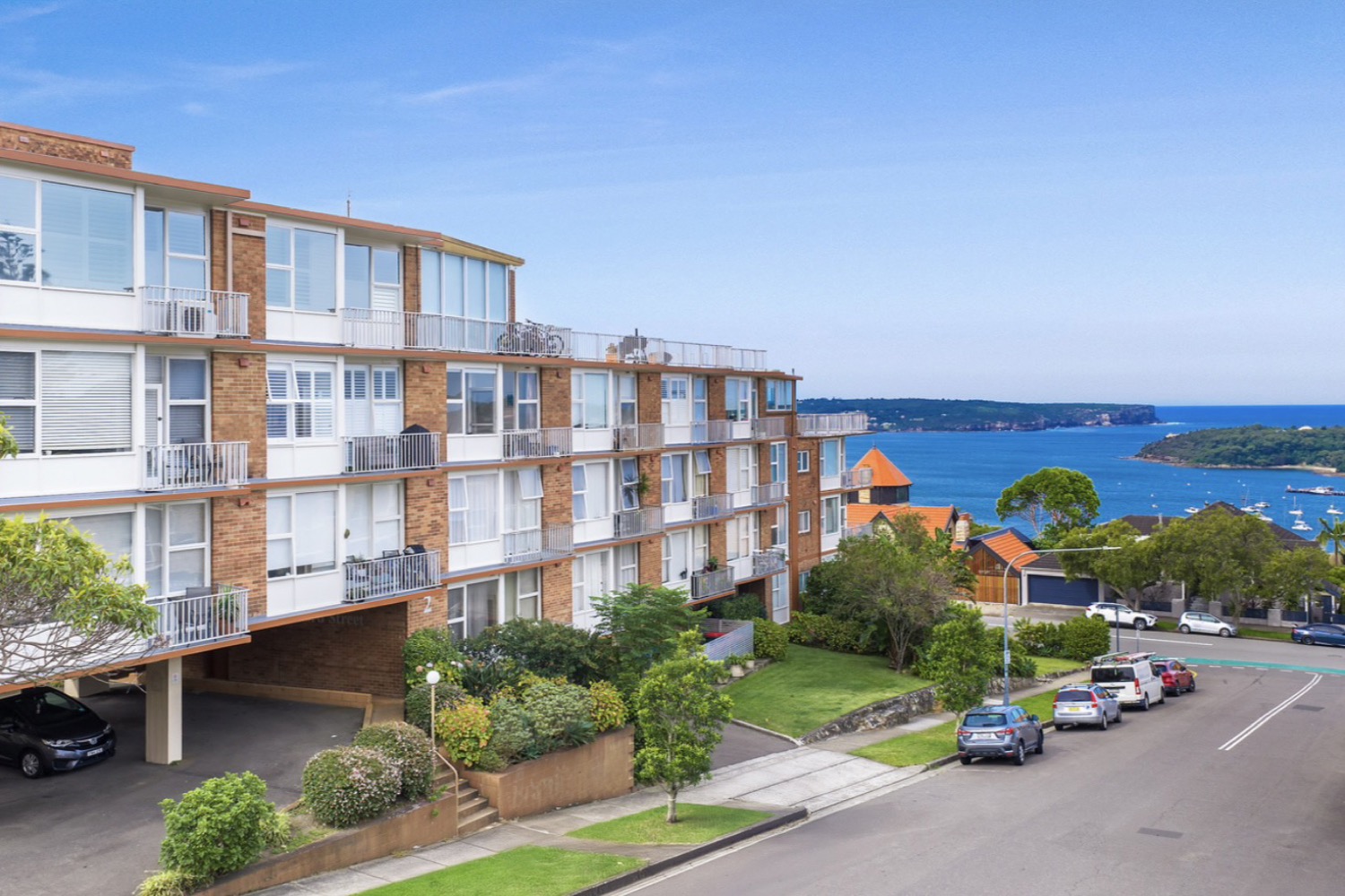 The 1960s apartment block at 2 Clifford Street, Mosman, with Middle Harbour and Balmoral behind it.