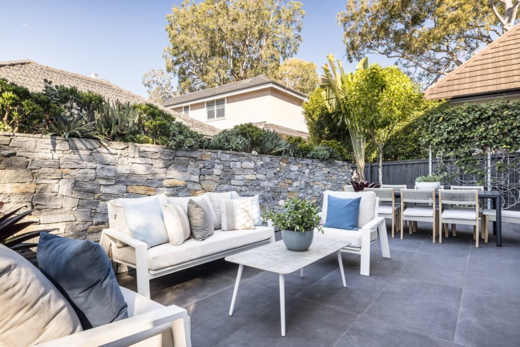 The wraparound alfresco terrace at 51 Young Lane, Cremorne, with a sandstone wall and outdoor lounge.