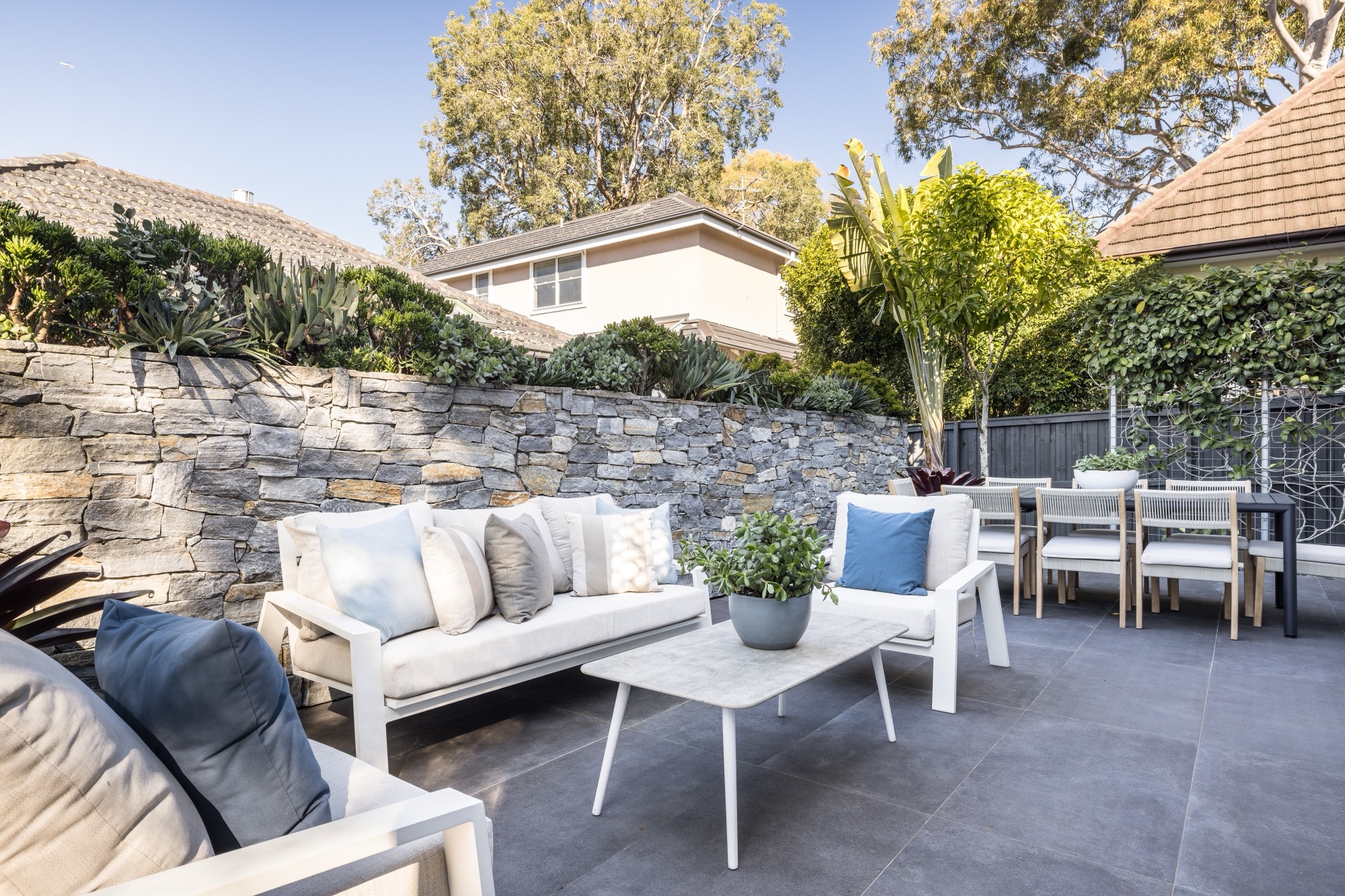 51-young-lane-cremorne-alfresco-terrace The wraparound alfresco terrace at 51 Young Lane, Cremorne, with a sandstone wall and outdoor lounge.