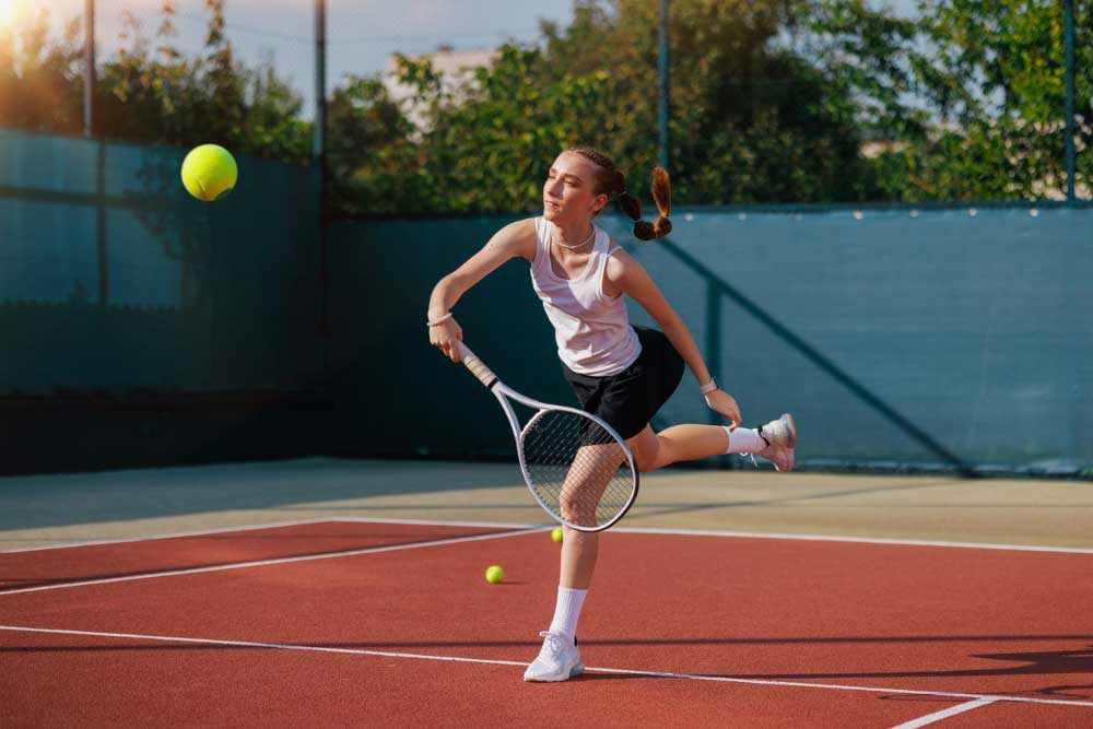 Young girl playing tennis with yellow ball in the foreground