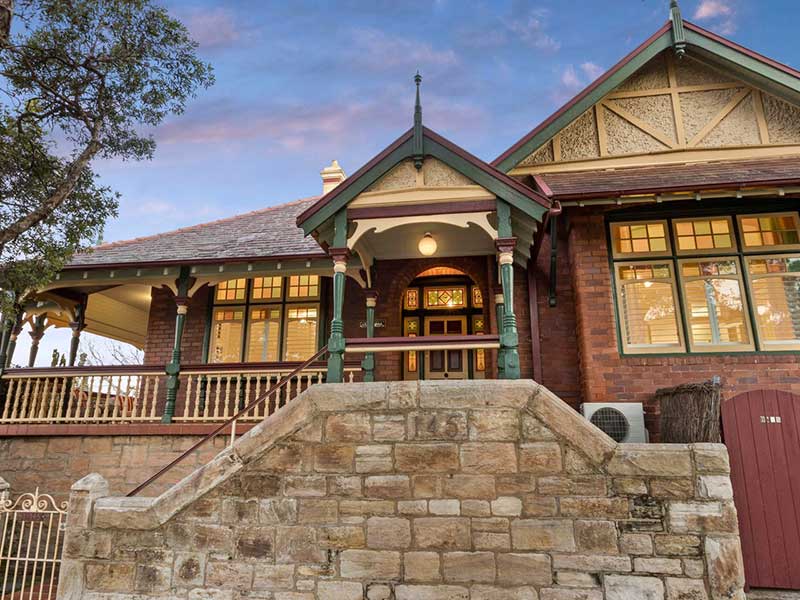 145a Raglan St, Mosman The red brick Federation house at 145a Raglan St, Mosman, with green timber gables, a leadlight front door and a sandstone retaining wall out the front.