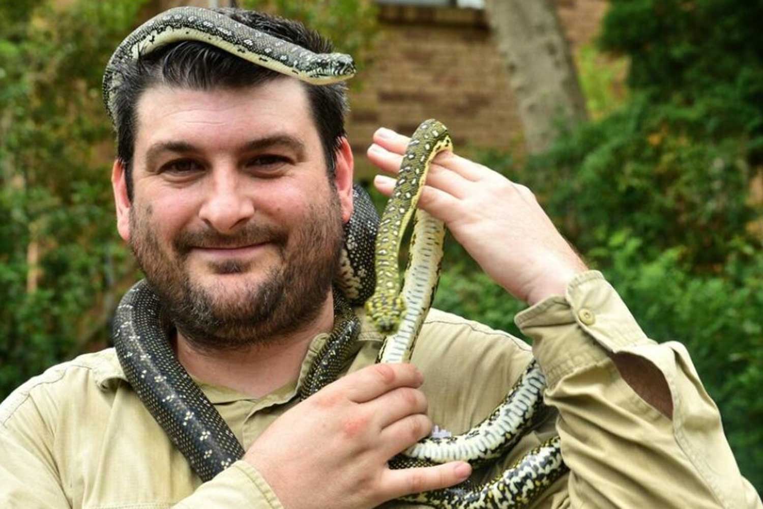 Harley Jones smiling with a python around his neck