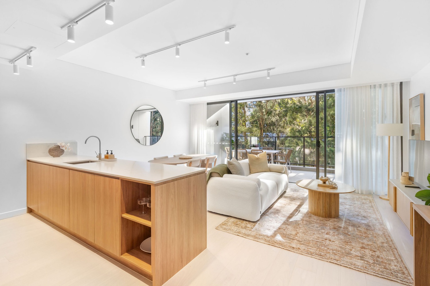 Open plan living and kitchen in a Northcote Collective apartment, Naremburn, opening to a balcony.